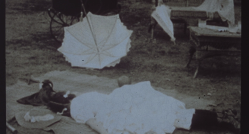 A Victorian child lies on the ground, an upturned parasol nearby. She could be asleep, but we're told this is a crime scene photo following a shocking murder.