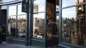 A shopfront with mannequins in the windows wearing tweed.