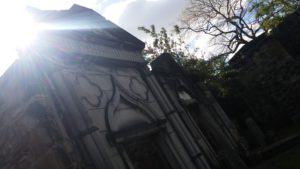 The sun peaks out from behind a large stone burial plot.