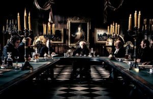 A grand room with scary looking men sitting around a table.